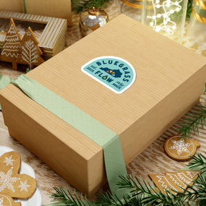 Gift box with a blue and white bluegrass flow logo on a festive background with cookies and decorations