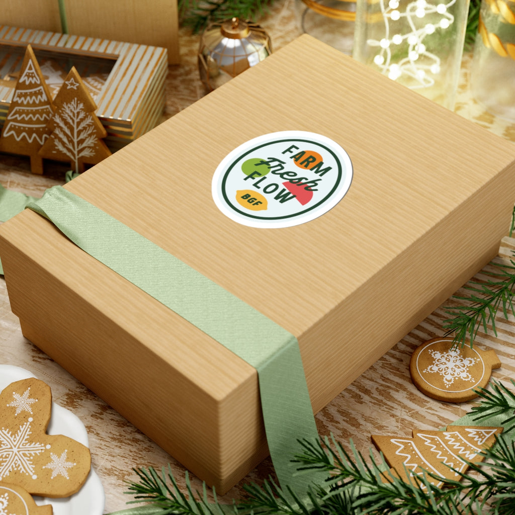 Gift box with a green ribbon and decorative bluegrass flow sticker on a festive background with cookies and lights.