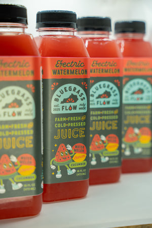 Row of Electric Watermelon juice bottles with colorful labels on a white surface.
